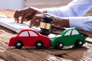 car accident lawyer typing next to a gavel and toy car crash